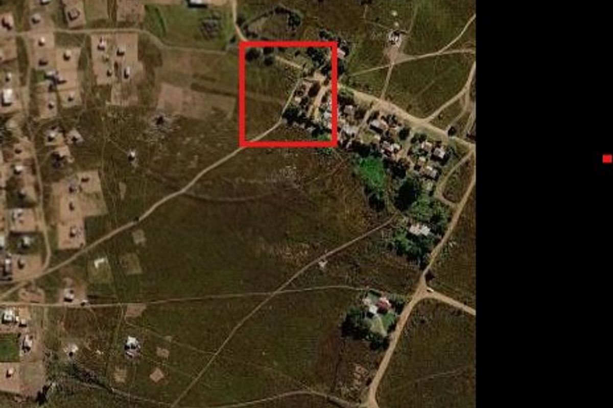 Aerial view of a vacant residential plot highlighted in red, situated within a developing rural or semi-rural residential area.