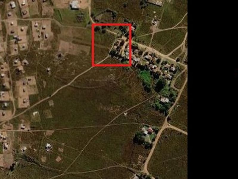 Aerial view of a vacant residential plot highlighted in red, situated within a developing rural or semi-rural residential area.