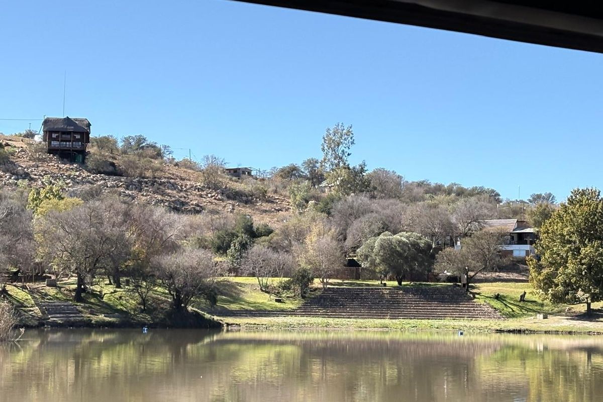 A scenic view of a tranquil lake with terraced landscaping and surrounding hillside terrain.