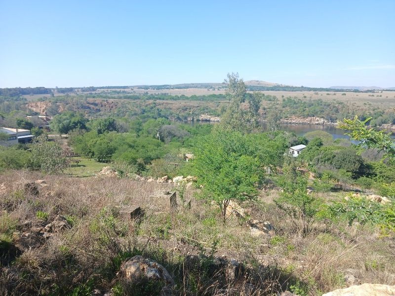 A scenic elevated view of the surrounding natural landscape, featuring lush greenery, rocky terrain, and a river flowing through the valley.