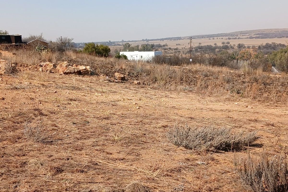 A wide-angle view of the vacant residential land, showcasing the natural landscape and surrounding rural terrain.