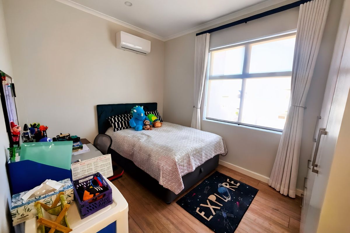 A well-maintained bedroom featuring laminate flooring, a split-system air conditioner, recessed downlighting, and a built-in wardrobe.