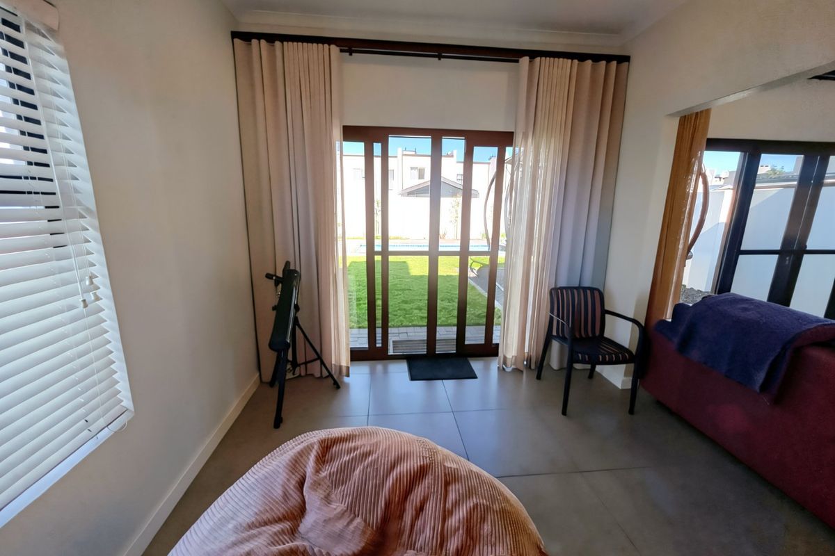 A bright living room featuring large sliding glass doors that provide direct access to the garden and pool area.