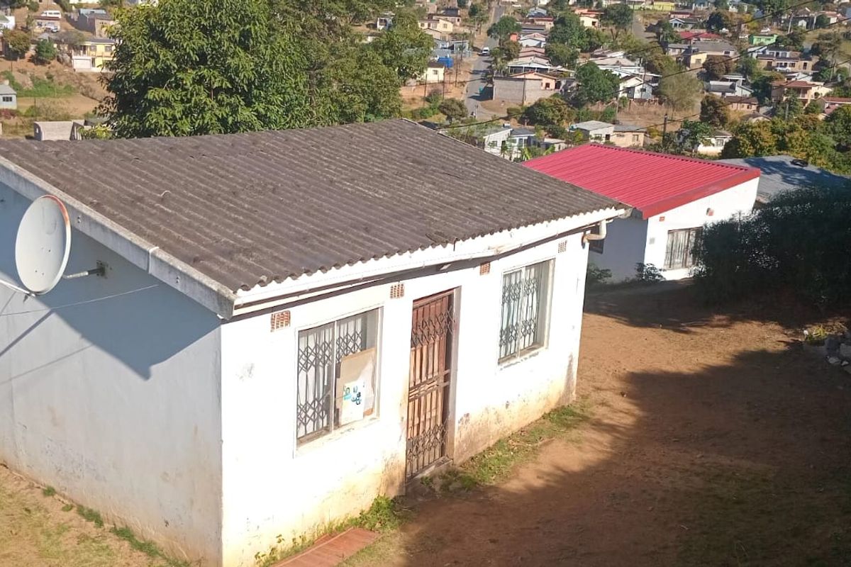 Aerial view of a residential property featuring a corrugated roof, security gates, and burglar bars, situated in a suburban neighborhood.