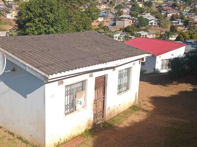 Aerial view of a residential property featuring a corrugated roof, security gates, and burglar bars, situated in a suburban neighborhood.