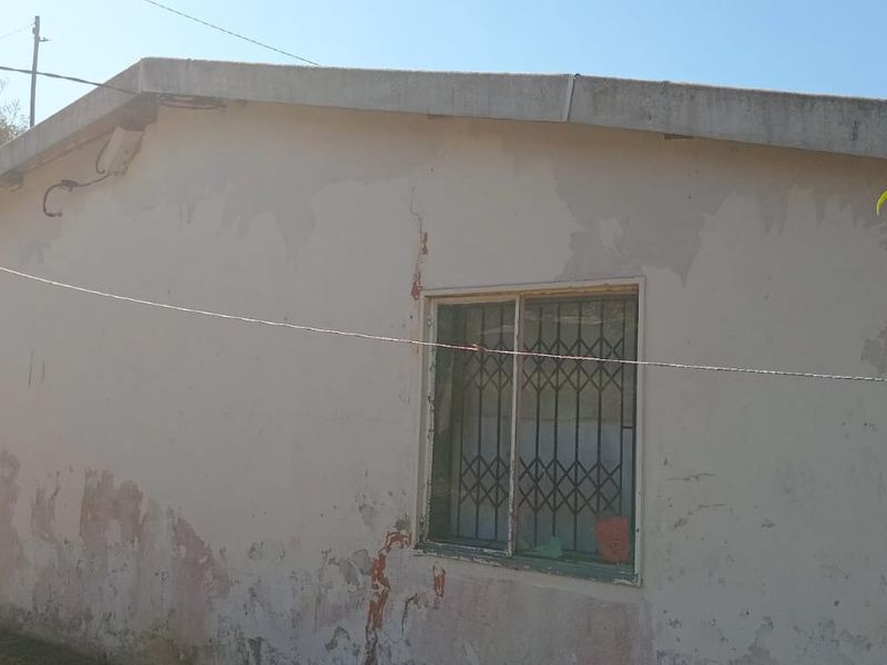 Rear exterior view of the property showing significant wear to the exterior wall finish and visible cracking, requiring maintenance and repainting.