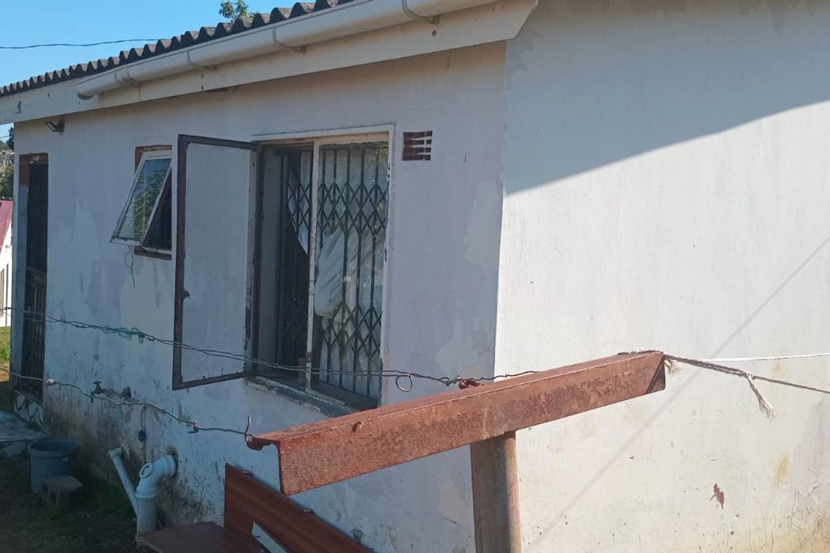 Rear view of a residential property showing exterior wall finishes, security bars on windows, and guttering system.