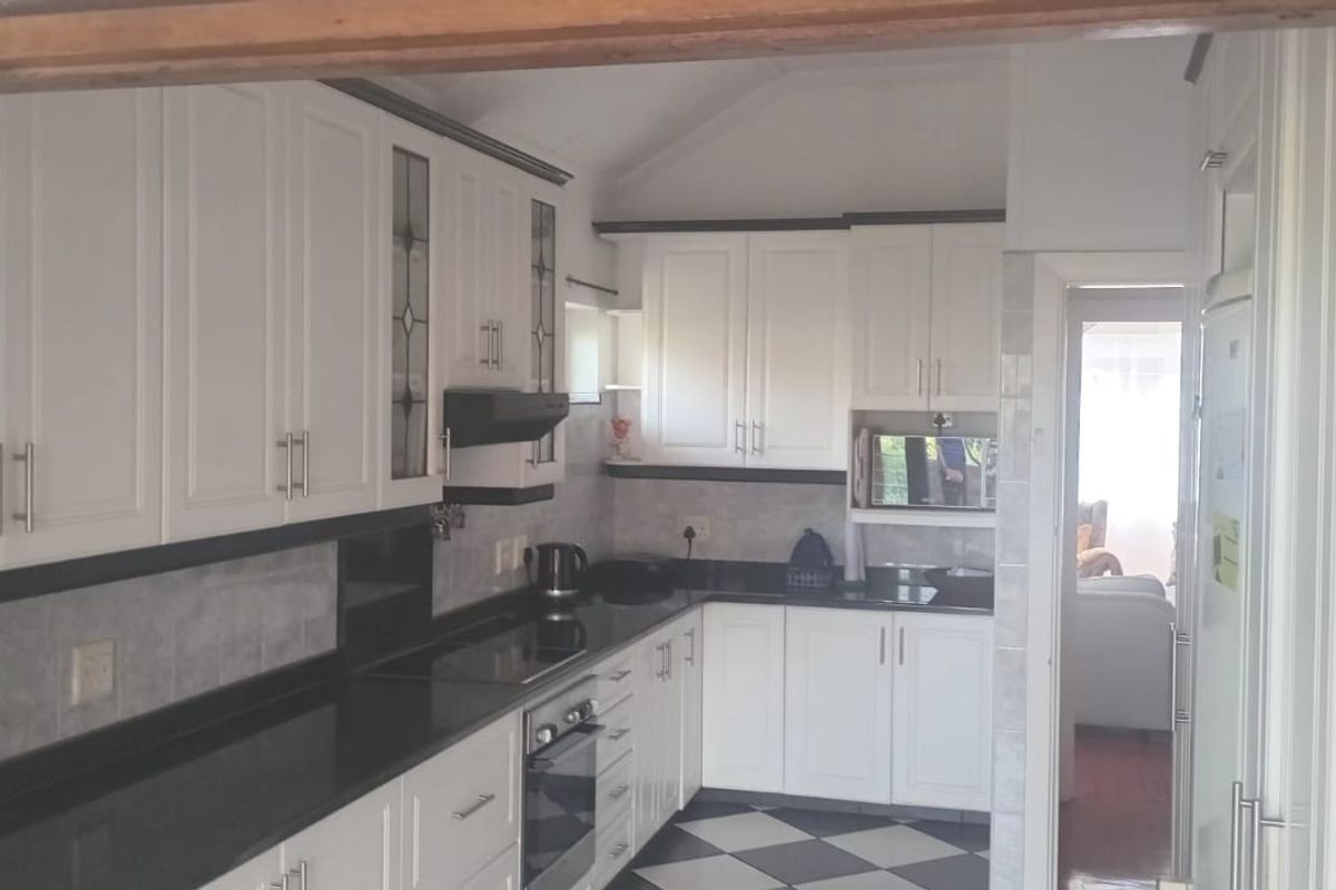 A functional kitchen featuring white cabinetry, dark granite countertops, a built-in oven, and a classic black and white checkered tiled floor.