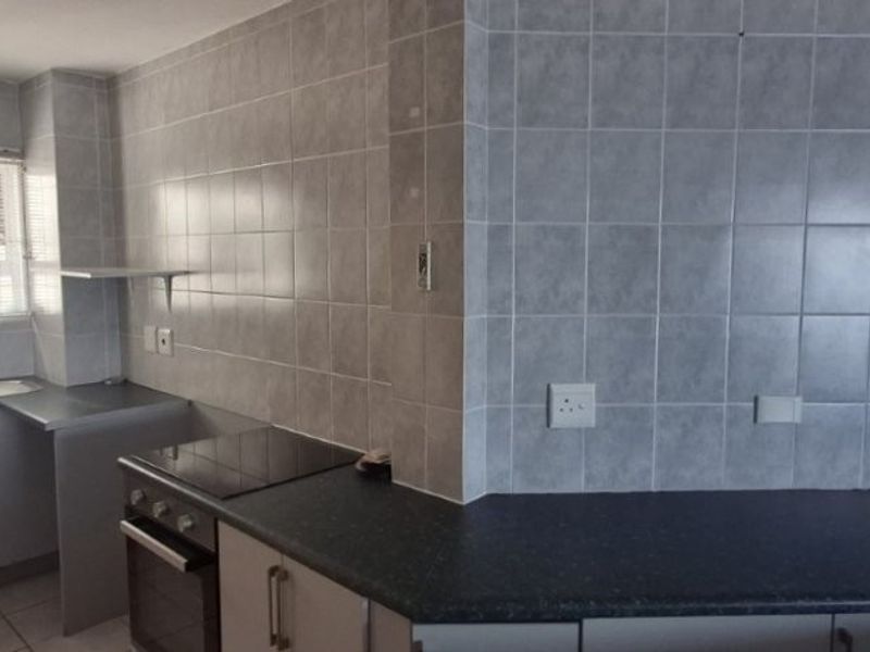 A functional kitchen featuring built-in cabinetry, laminate countertops, a stainless steel sink, and a built-in oven with an electric hob.