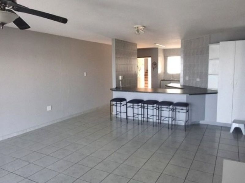 Open plan living and kitchen area featuring tiled flooring, a breakfast bar, and built-in cabinetry, providing a functional and versatile living space.