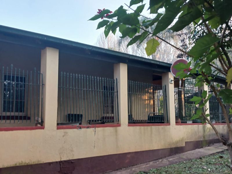 A covered patio area featuring concrete pillars and metal security fencing, showing signs of wear on the lower exterior wall finishes.