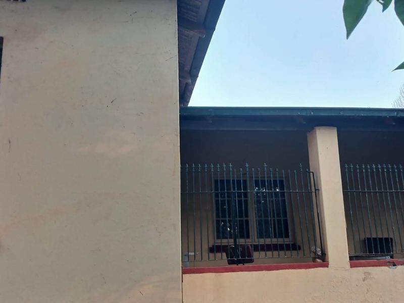Rear exterior view of the property featuring a covered veranda with metal security bars and multi-pane windows.