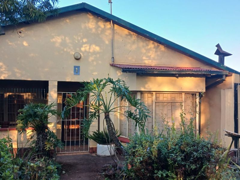 Front elevation of a single-story house featuring a metal roof, security bars on windows, and a covered entrance area with a security gate.