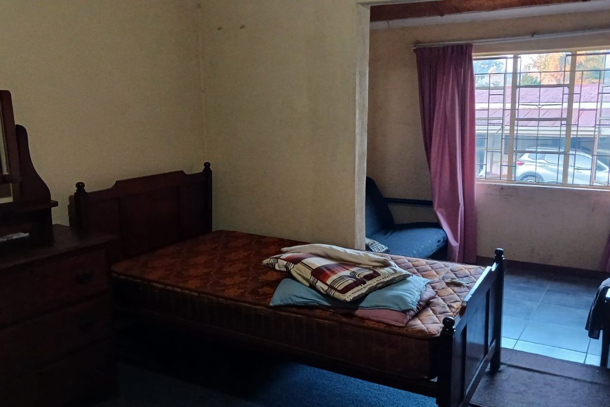 A bedroom featuring tiled flooring and a window with natural light, currently requiring cosmetic updates to improve the overall aesthetic.