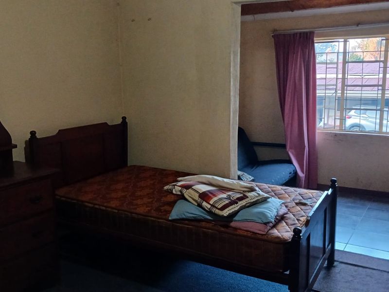 A bedroom featuring tiled flooring and a window with natural light, currently requiring cosmetic updates to improve the overall aesthetic.