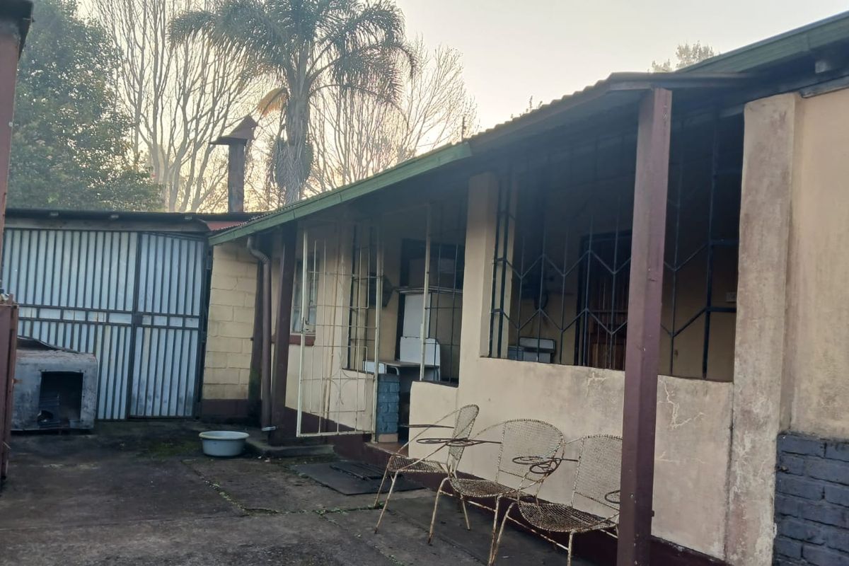 Rear exterior view of the property featuring a covered patio area with security bars and concrete paving.