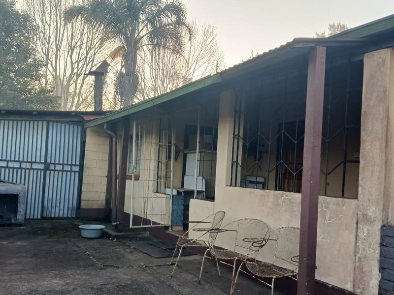 Rear exterior view of the property featuring a covered patio area with security bars and concrete paving.