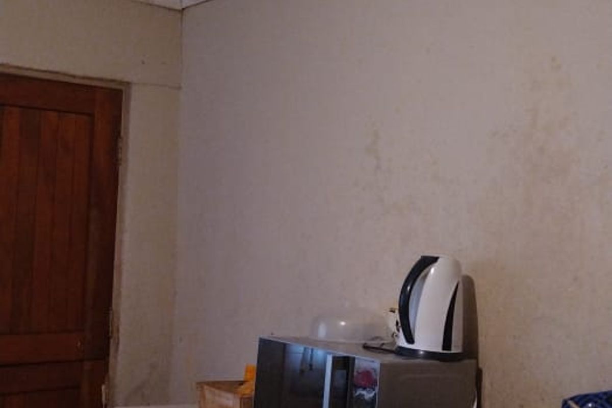 A dated kitchen area featuring built-in cabinetry and tiled flooring, showing visible signs of water damage on the walls and ceiling.