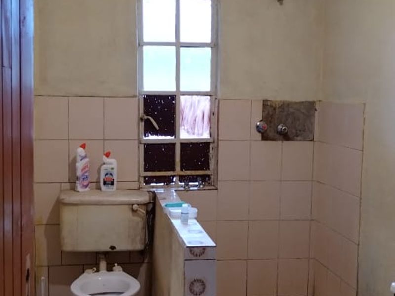 A dated bathroom featuring tiled flooring and walls, currently requiring significant renovation and fixture updates to improve functionality and aesthetic appeal.