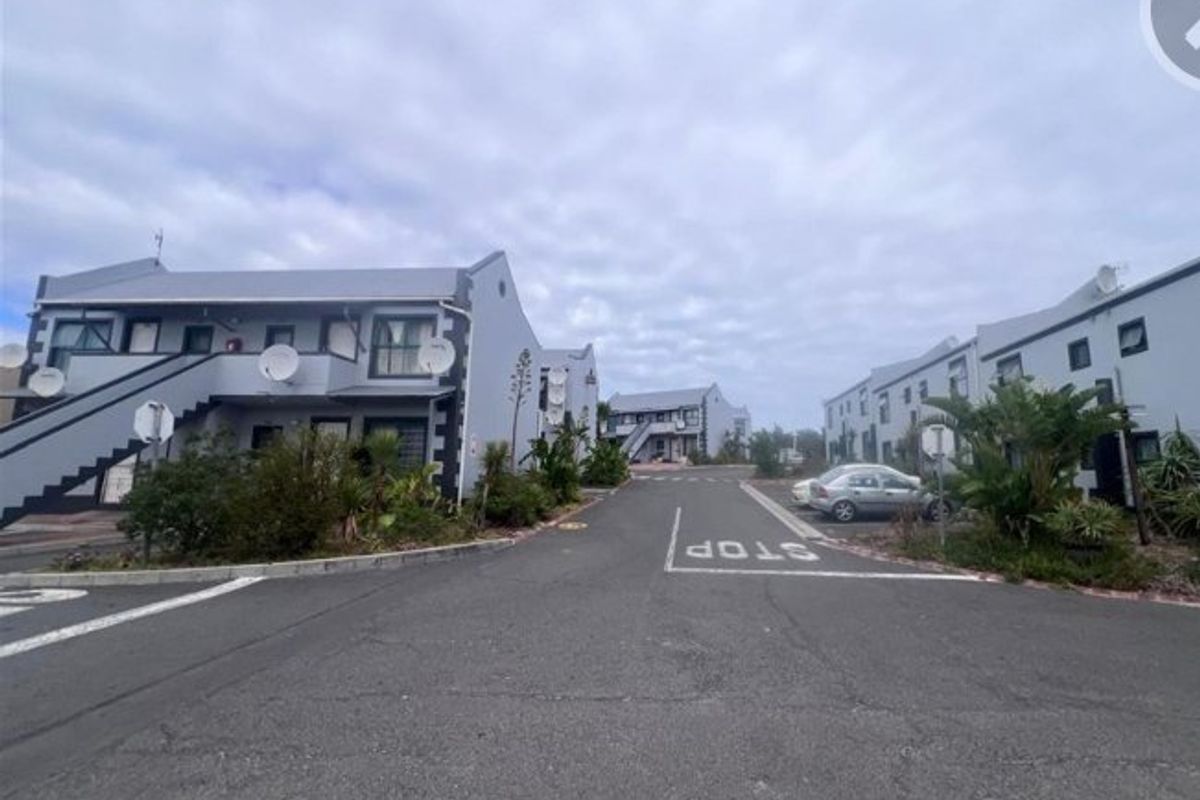 A street-level view of an apartment complex featuring multiple multi-story residential buildings with external staircases and paved access roads.
