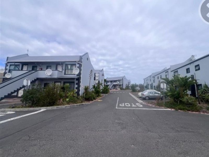 A street-level view of an apartment complex featuring multiple multi-story residential buildings with external staircases and paved access roads.