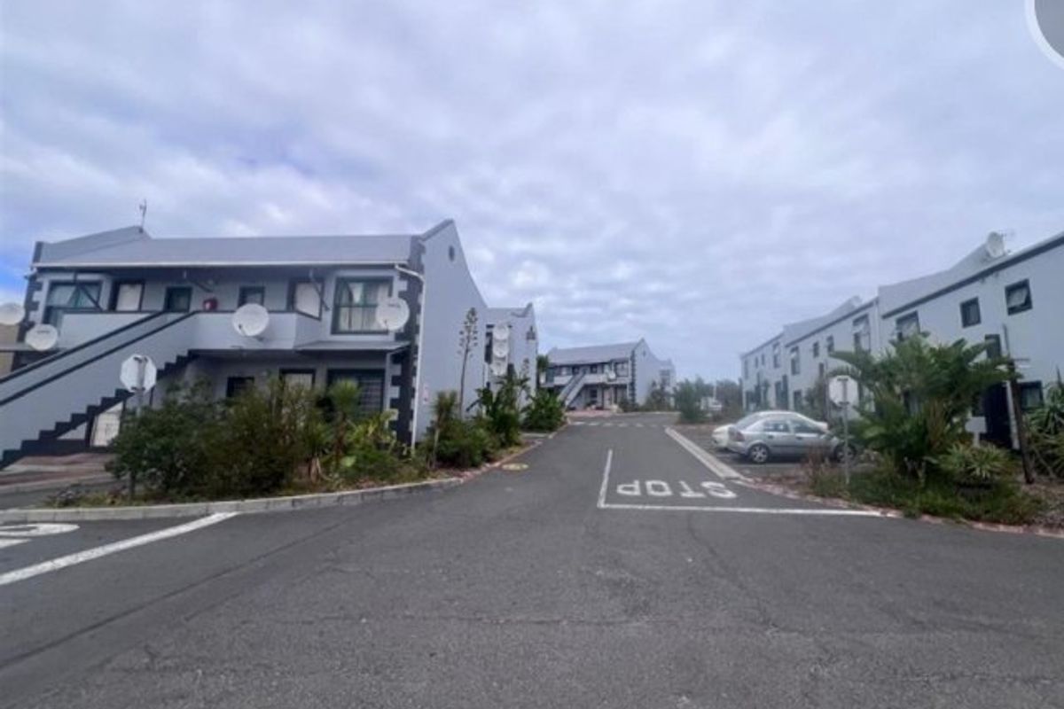 A street-level view of an apartment complex featuring multiple residential blocks, paved access roads, and external staircases.