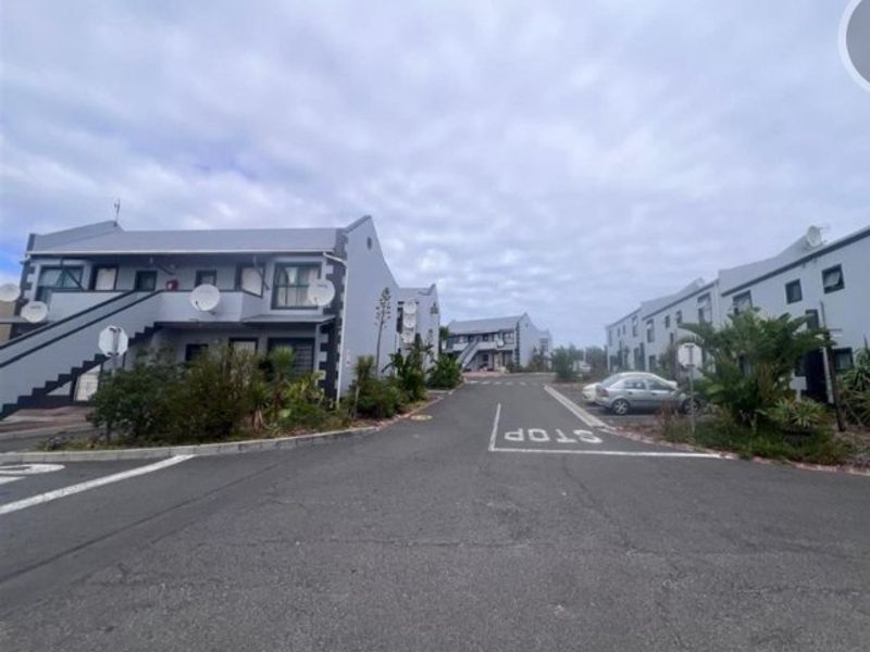 A street-level view of an apartment complex featuring multiple residential blocks, paved access roads, and external staircases.