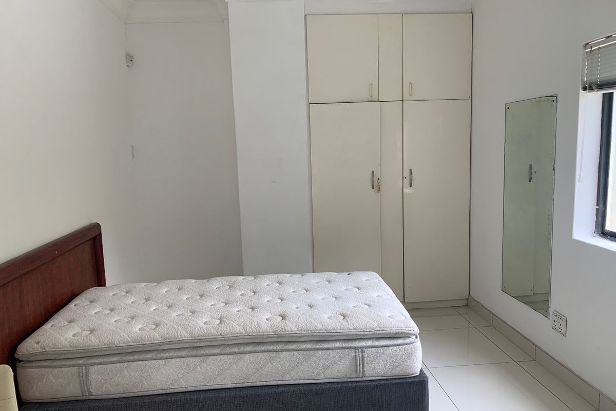 A bedroom featuring tiled flooring, built-in cupboards, and cornicing, offering a functional space ready for personal updates.