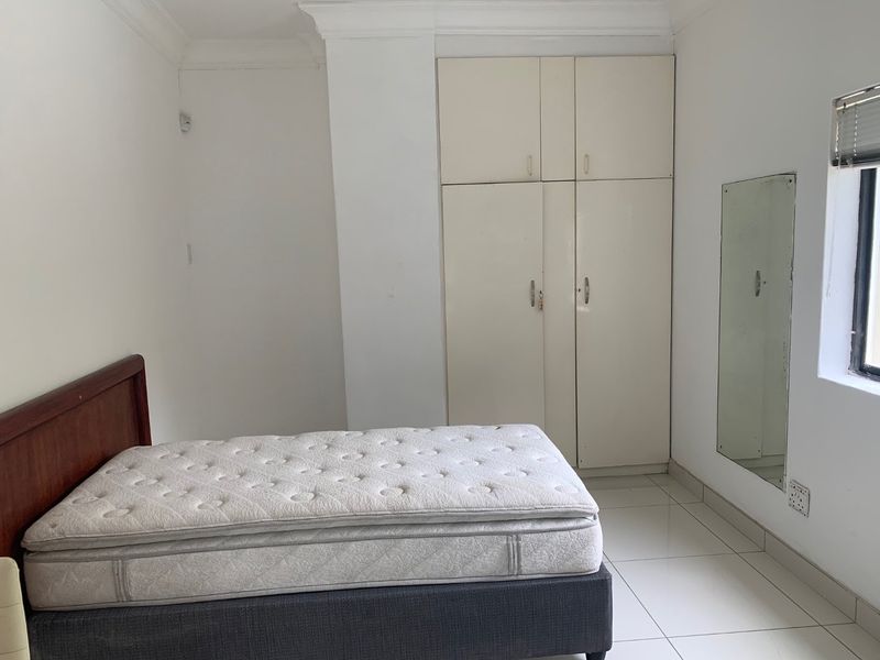 A bedroom featuring tiled flooring, built-in cupboards, and cornicing, offering a functional space ready for personal updates.