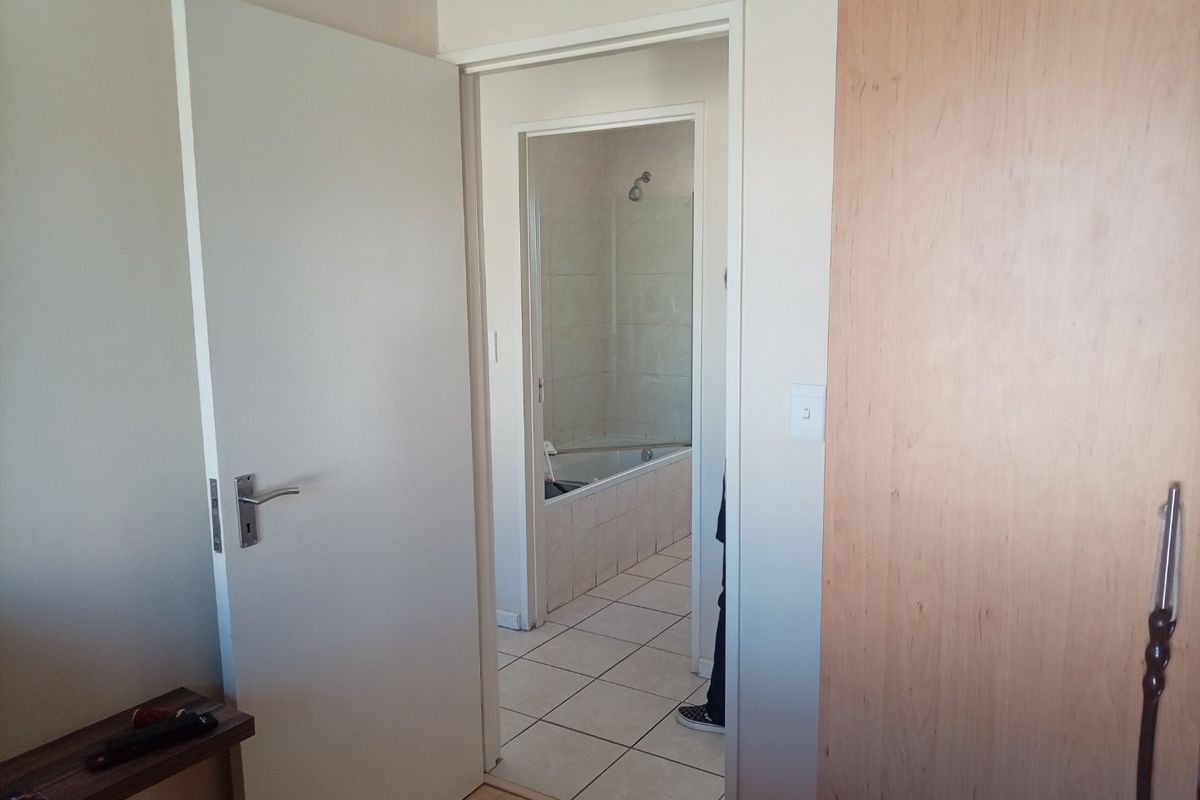 A view from a bedroom looking into an en-suite bathroom featuring tiled floors and a built-in cupboard.