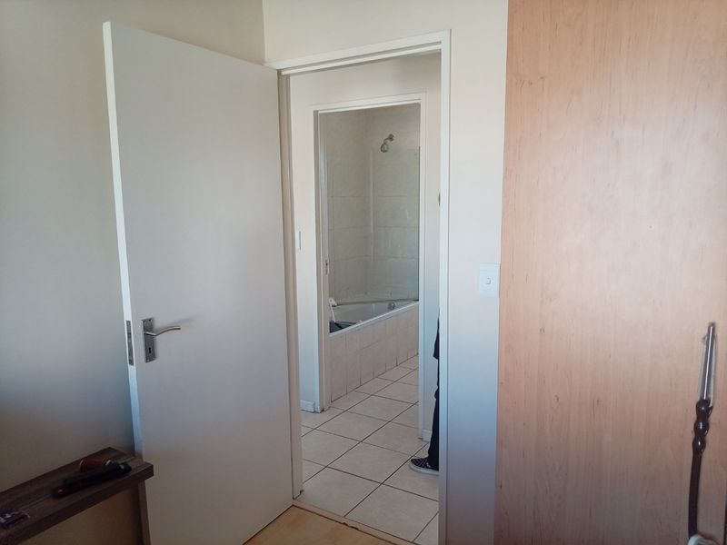 A view from a bedroom looking into an en-suite bathroom featuring tiled floors and a built-in cupboard.