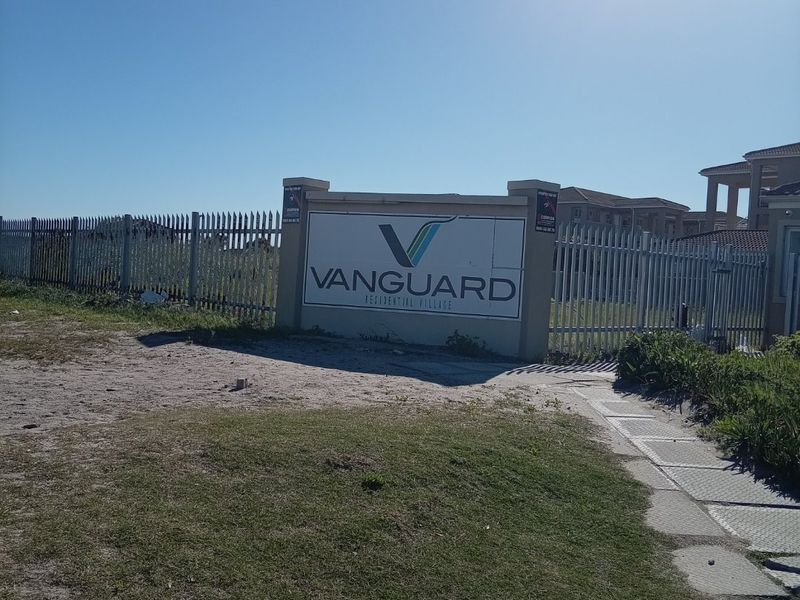 Entrance view of Vanguard Residential Village featuring security fencing and estate signage.