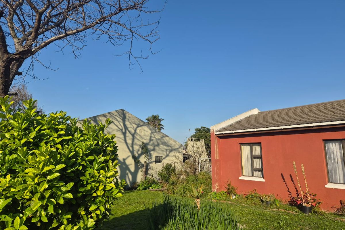 A view of the rear exterior of the house featuring a red painted facade, tiled roof, and a garden area.