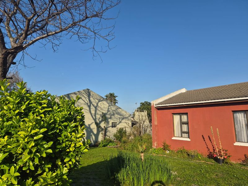 A view of the rear exterior of the house featuring a red painted facade, tiled roof, and a garden area.
