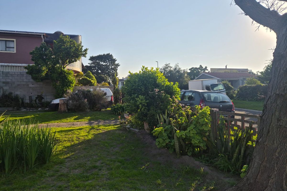 A view of the property garden featuring a lawn, mature trees, and a boundary fence.