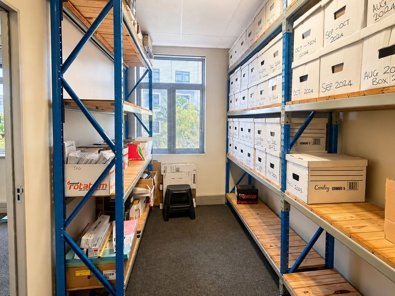 A functional utility or storage room featuring industrial metal shelving units and carpeted flooring, suitable for document or inventory organization.