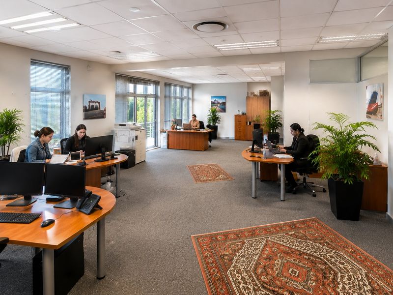 Spacious open-plan commercial office featuring large windows, suspended ceilings with recessed lighting, and extensive built-in storage cabinetry.