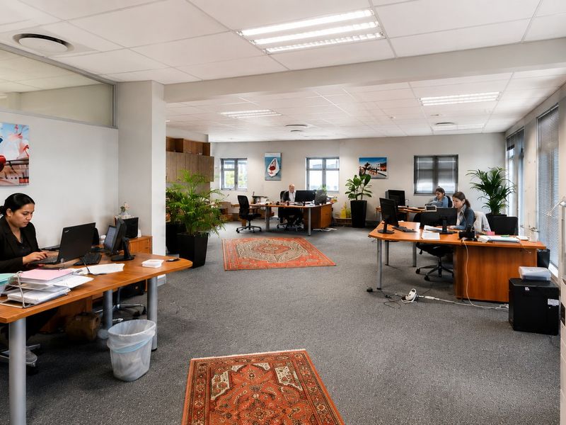 Spacious open-plan commercial office featuring suspended ceilings, recessed lighting, carpeted floors, and large windows with venetian blinds providing ample natural light.