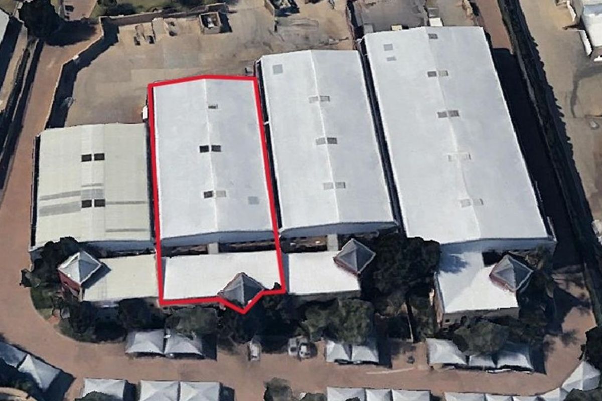 Aerial view of an industrial warehouse complex featuring metal roofing, skylights, and surrounding paved yard space.