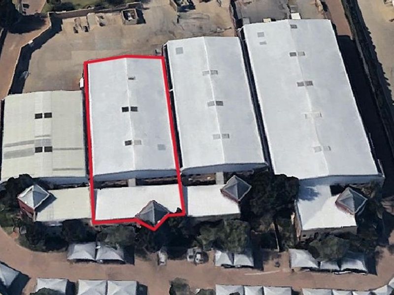 Aerial view of an industrial warehouse complex featuring metal roofing, skylights, and surrounding paved yard space.