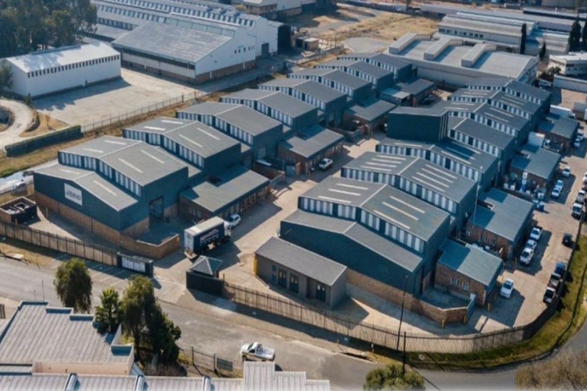 Aerial view of an industrial warehouse complex featuring multiple units with metal roofing, secure perimeter fencing, and paved access roads.