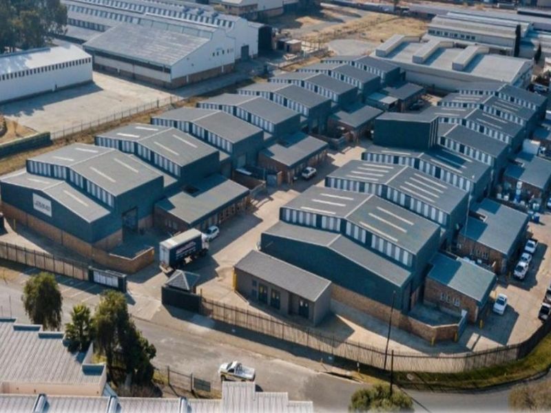 Aerial view of an industrial warehouse complex featuring multiple units with metal roofing, secure perimeter fencing, and paved access roads.
