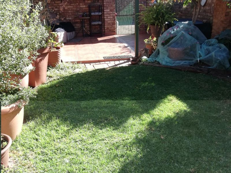 A private rear garden featuring a covered patio area with brick walls, tiled flooring, and a small lawn.