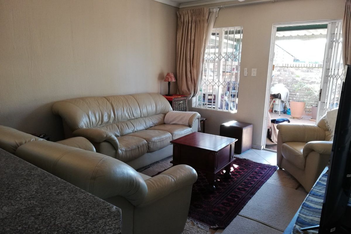 A living room area featuring a ceiling fan, security gates, and direct access to an outdoor patio space.