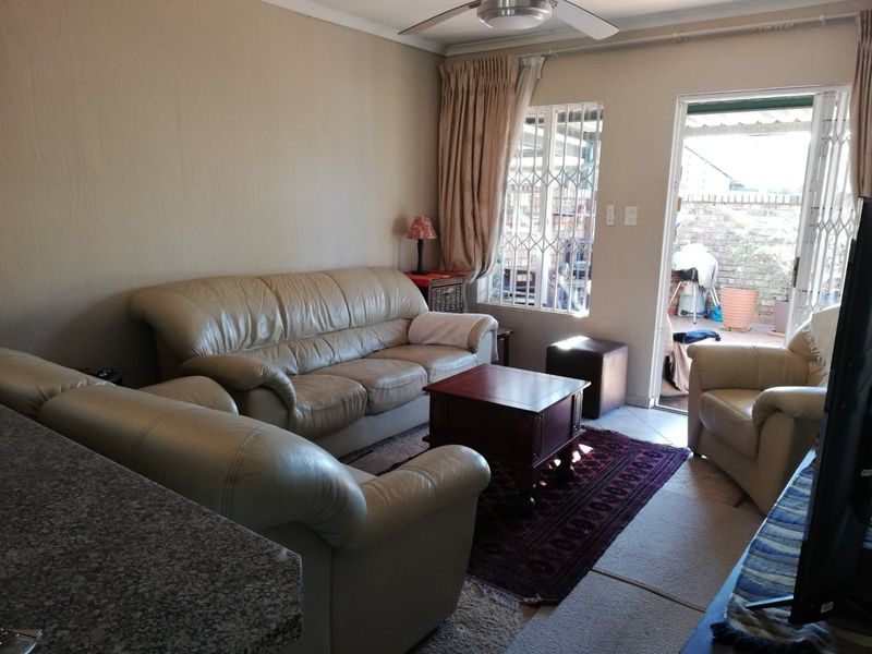 A living room area featuring a ceiling fan, security gates, and direct access to an outdoor patio space.