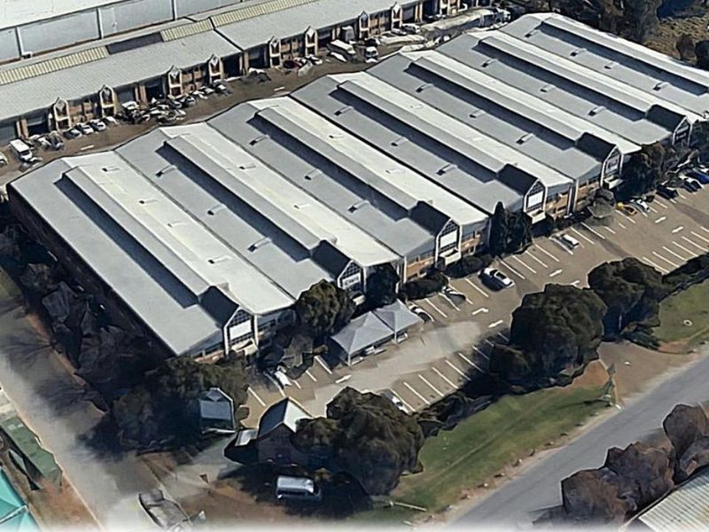 Aerial view of an industrial warehouse complex featuring extensive metal roofing, dedicated parking bays, and surrounding landscaped areas.