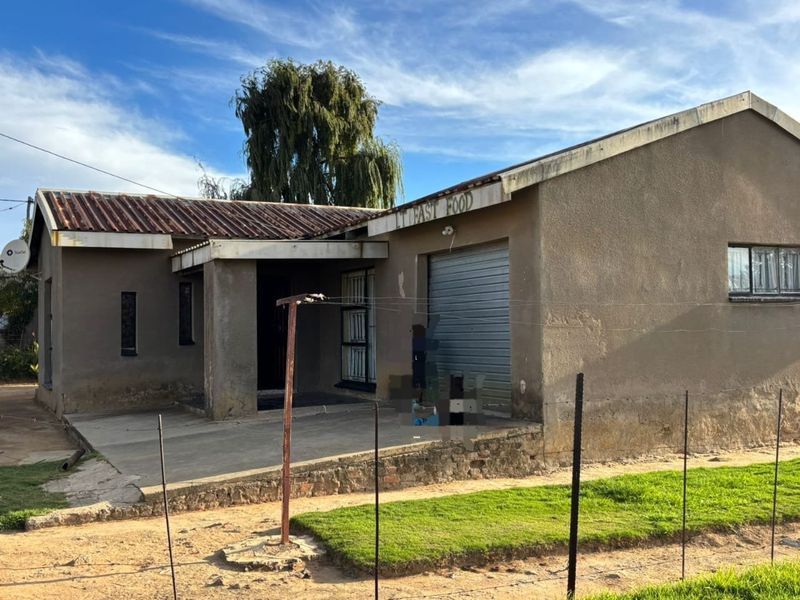 Front exterior view of a single-story property featuring a roller shutter door, concrete porch, and security bars on windows.