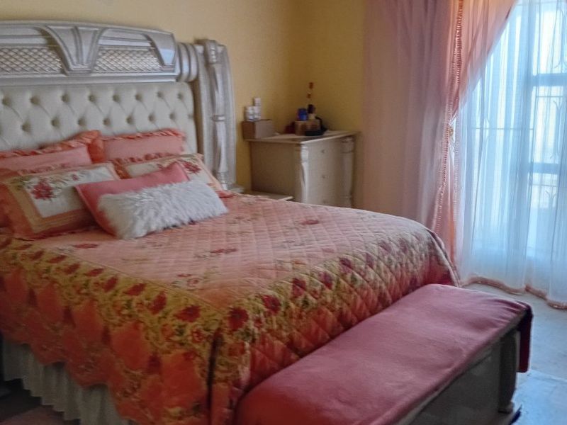 A bedroom featuring yellow walls, coving, and a window with draped curtains.