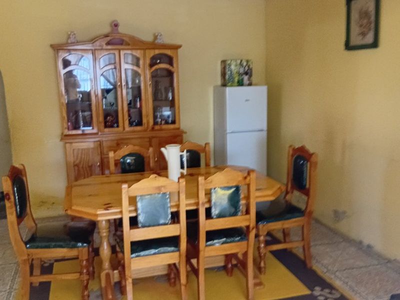 A dining area featuring ceramic tiled flooring and coved ceilings, currently requiring cosmetic updates to the wall finishes and general maintenance.