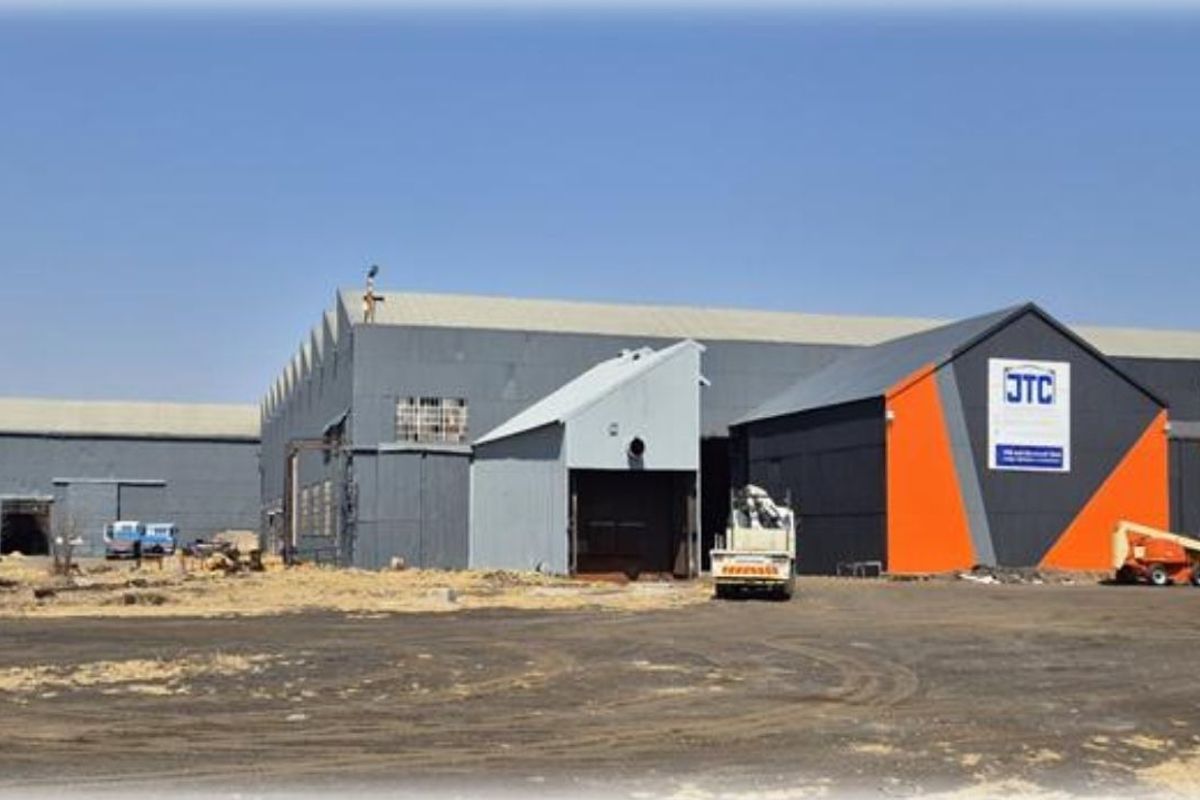 Exterior view of a large industrial warehouse facility featuring metal cladding, roller shutter access, and an expansive yard area.